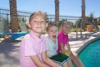 Three children sitting by a pool.