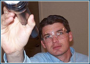 Male exterminator wearing protective goggles and shining flashlight.