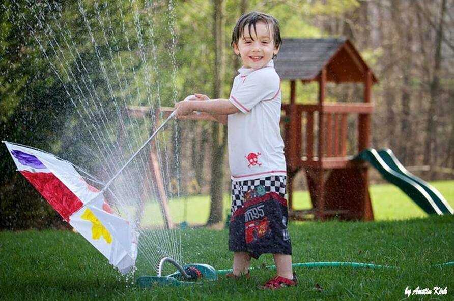 A toddler playing in the sprinkler.