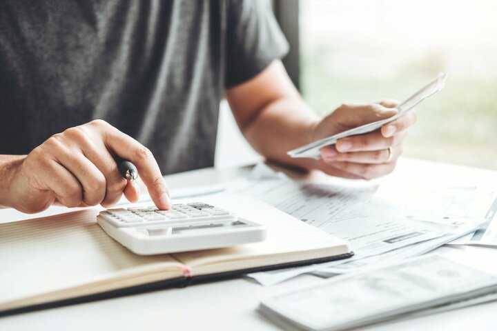 A man types on a calculator while balancing a checkbook