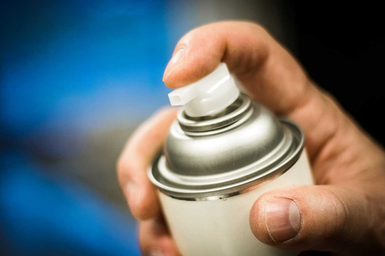 A hand holding an aerosol can, ready to spray
